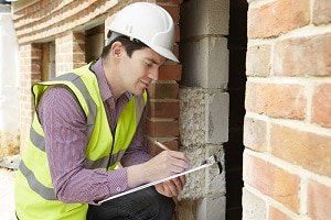 Man checking a home holding a clip board